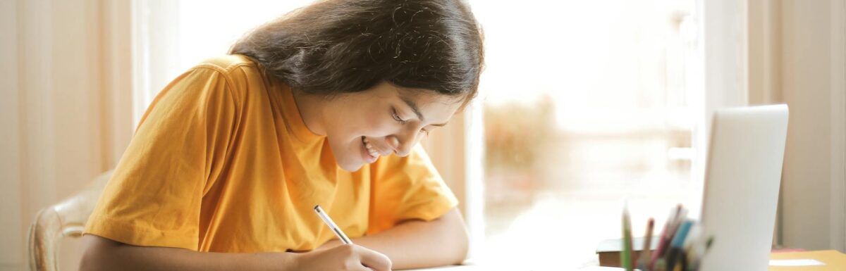 woman in yellow shirt writing on white paper